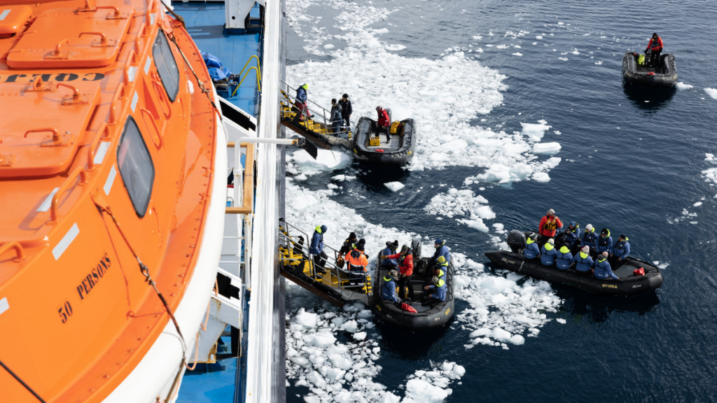 Four Zodiacs depart from a ship in icy waters